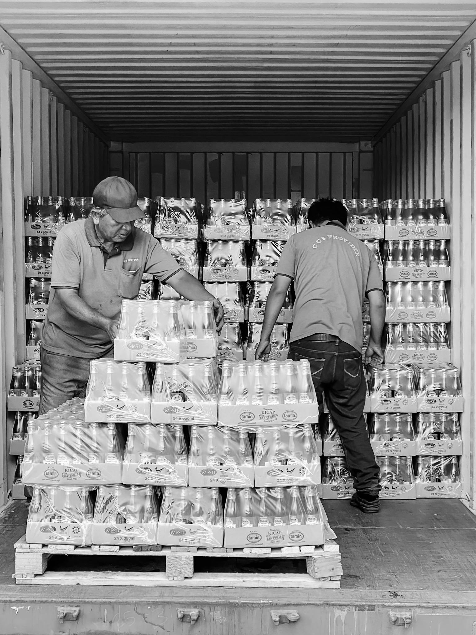 Two workers organize products in a shipping container in Ipoh, Malaysia.